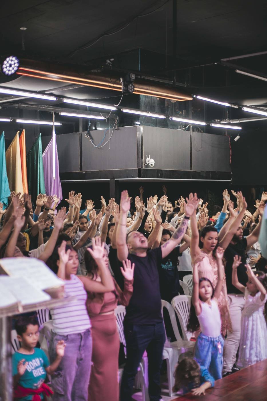 Igreja reunida em adoração, com as mãos levantadas